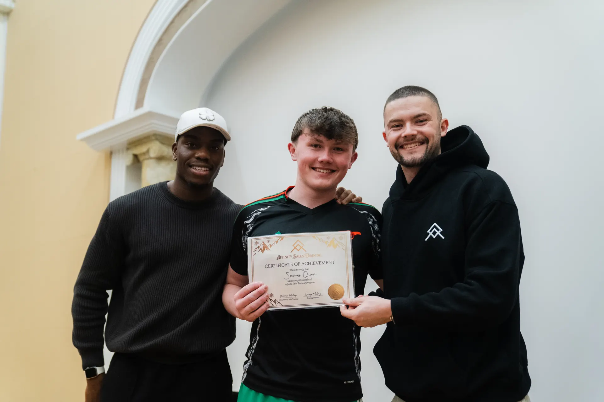 An Affinity graduate flanked by the two founders